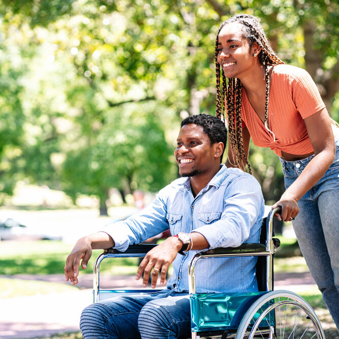 Man in a wheelchair enjoying a walk with his girlfriend.